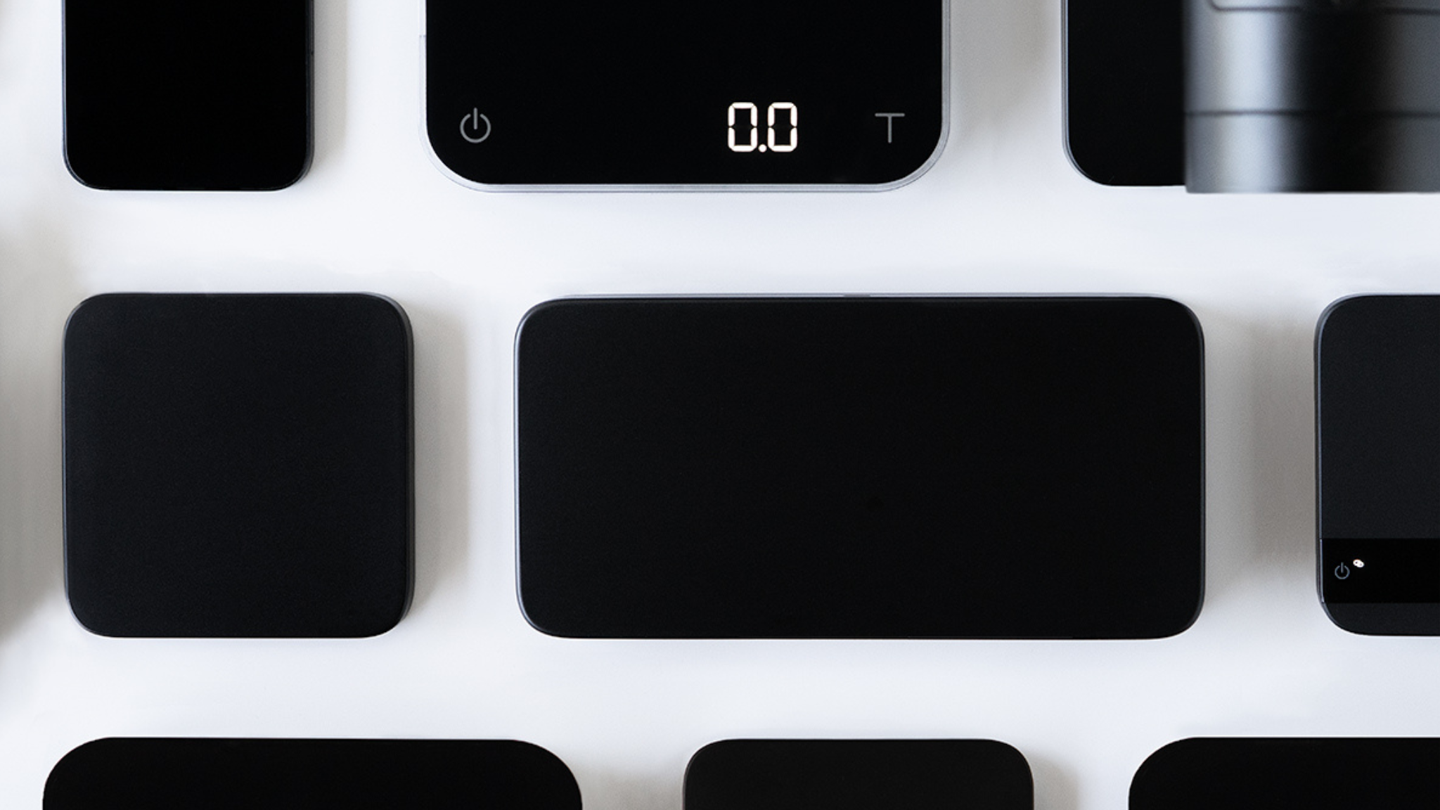 Several Acaia products in the black colorway against a white background, including the Umbra Lunar, Umbra Lunar Duo, Pearl, Lunar, and more.